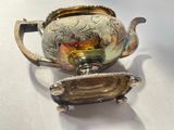 a silver tea pot with a handle on a white table