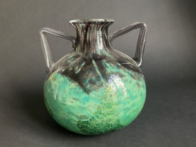 a green and black vase sitting on a table