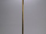 a brass floor lamp with a white shade on top of it