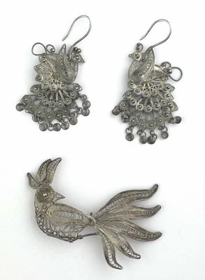 three pieces of silver jewelry are displayed on a white surface