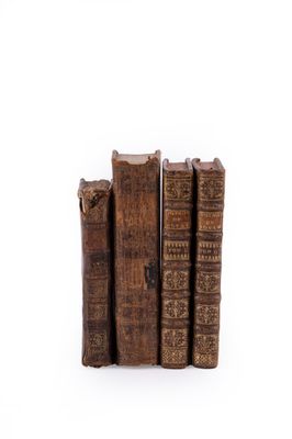 several old books stacked on top of each other on a white surface