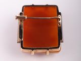 a close up of a ring with an orange stone in it