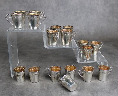 plusieurs coupes en argent et des plateaux de couverts en argent posés sur une table