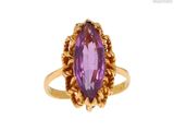 gros plan d'une bague en or avec une pierre violette
