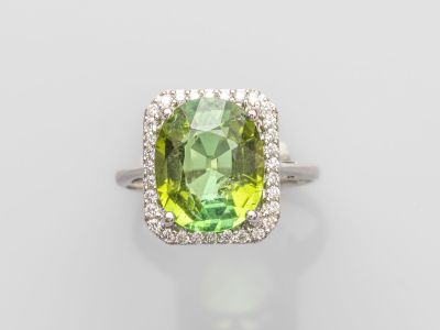 gros plan d'une bague avec une pierre verte entourée de diamants blancs