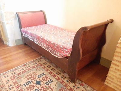 lit en bois massif de style traîneau dans une chambre où un tapis recouvre le sol