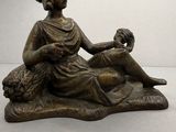 statue en bronze représentant une femme assise sur un rocher avec un chien