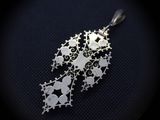 a close up of a silver pendant on a black surface
