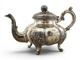 une vieille théière en argent surmontée d'un oiseau