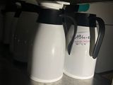 deux cafetières, une blanche et une noire, posées sur une étagère
