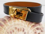 the black leather bracelet has a gold buckle on it