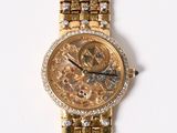 a gold wrist watch with diamonds on it on a white surface