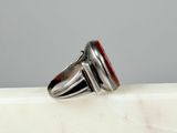 silver ring with a red stone in the center on a white marble surface
