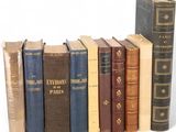 several old books are lined up in a row on a white surface