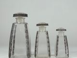 three small glass bottles with silver lids on a white surface