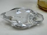 a glass ashtray on a table next to a glass bottle