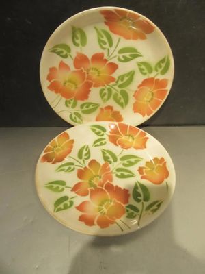 two plates with orange flowers on them sitting on a table