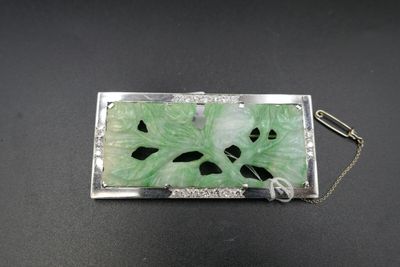 un gros plan sur une broche verte attachée à une chaîne, posée sur une table