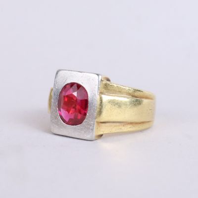 a close up of a gold and silver ring with a red stone