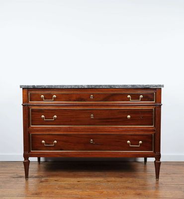 une commode en bois avec un plateau en marbre, posée sur un parquet