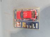 a red toy car in a plastic package on a table