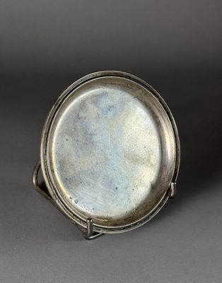 an old silver plate sitting on top of a gray surface