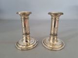pair of silver candlesticks on a table with a white background