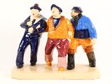 three figurines of three men sitting on a bench
