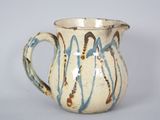 a white pitcher with blue and brown designs on it