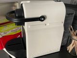a white coffee maker sitting on a counter next to a cup of coffee