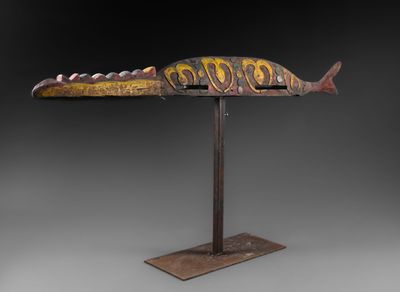 une sculpture en bois représentant un poisson, posée sur un socle en métal