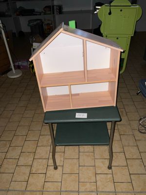 une petite table sur laquelle est posée une maison de poupées