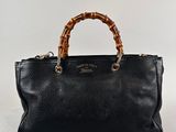 a black leather handbag with bamboo handles on a white background