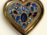 a gold heart shaped brooch with blue stones on it