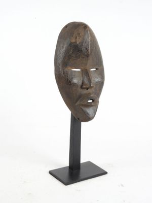 an image of a wooden mask on a black stand on a white background