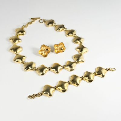 un ensemble composé d'un collier, d'un bracelet et de boucles d'oreilles en or, sur fond blanc