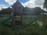 a wooden swing set in the middle of a grassy field