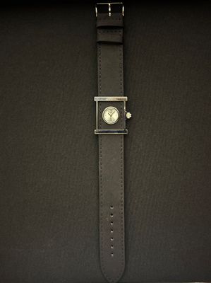 un gros plan sur un sac noir orné d'une montre argentée