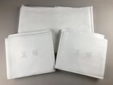 trois serviettes blanches ornées de monogrammes brodés, posées sur une table