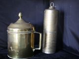 une cafetière en or à côté d'une cafetière en argent, posées sur un tissu noir