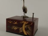 statue of a crane on a wooden box with a white background