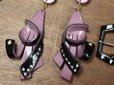 a pair of pink and black earrings sitting on a table