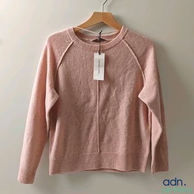 un pull rose suspendu à un cintre accroché au mur