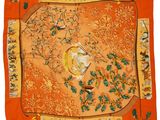 un foulard en soie orange orné d'oiseaux et de fleurs