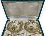 two tea cups and saucers in a box with a spoon and spoon