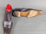 pair of men ' s shoes with red soles on a gray surface