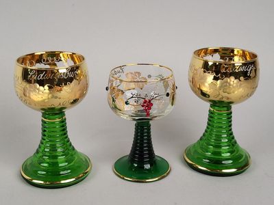trois gobelets verts et dorés posés les uns à côté des autres sur une surface blanche