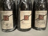 three bottles of wine wrapped in plastic sitting on a counter