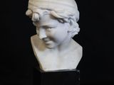 a white marble bust of a woman with a hat on her head