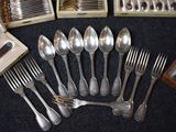 many spoons and forks laid out on a table